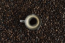 Glas schwarzer Kaffee zwischen Kaffeebohnen — Stockfoto