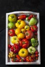 Wooden tray of various sorts of tomatoes — Stock Photo