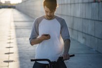Jeune homme avec vélo fixie banlieue regardant le téléphone portable — Photo de stock
