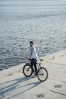 Молодий чоловік з приміського велосипеда fixie маючи перерву на березі річки — стокове фото