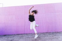 Екстремальна молода жінка стрибає перед рожевою стіною — стокове фото