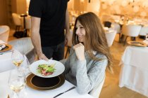 Cameriere servire piatto per donna sorridente in un ristorante — Foto stock