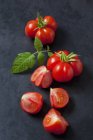Цільні і нарізані помідори чері ' Voyage ' на темному грунті — стокове фото