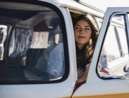Pretty woman on a road trip with her camper, looking out of car window — Stock Photo