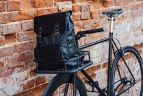 Backpack in cargo cage of acustomised commuter fixie bike at brick wall — Stock Photo