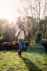 Vater spielt mit seinem Sohn und trägt ihn huckepack im Garten — Stockfoto