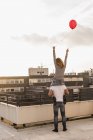 Back view of young couple on roof terrace at sunset — Stock Photo