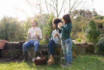 Familia feliz sentada en el jardín, tomando un descanso, comiendo sándwiches - foto de stock
