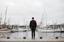 Visão traseira de um jovem com roupas casuais olhando para o porto — Fotografia de Stock