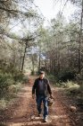 Retrato de homem sênior sorridente andando com cesta cheia de cogumelos na floresta — Fotografia de Stock