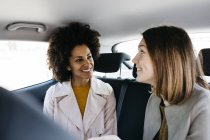 Zwei glückliche Frauen auf dem Rücksitz eines Autos — Stockfoto