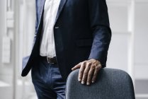 Uomo d'affari in piedi dietro la sedia da ufficio, vista parziale — Foto stock