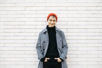 Portrait of stylish young man wearing cap, black turtleneck pullover and grey coat — Stock Photo