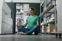 Sorrindo mulher grávida sentada no chão no escritório tendo uma pausa de ioga — Fotografia de Stock