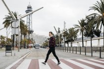 Молодой человек в повседневной одежде ходит по пешеходному переходу в Барселоне — стоковое фото