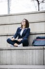 Empresária sentada ao ar livre nas escadas com laptop olhando para cima — Fotografia de Stock
