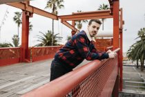 Giovane uomo con abiti casual su un ponte rosso guardando la fotocamera — Foto stock
