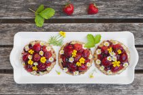 Tartelettes de coeur de fraise maison avec fleurs de marguerite et souci doré, fleurs comestibles, bois foncé — Photo de stock