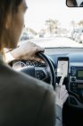 Donna che guida in auto attraverso la città utilizzando un'app di navigazione telefonica — Foto stock