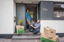 Couple at house entrance with cardboard boxes — Stock Photo