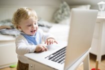 Маленький мальчик дома играет с ноутбуком — стоковое фото