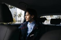 Мужчина, сидящий на заднем сиденье машины и выглядывающий в окно — стоковое фото