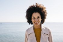 Портрет улыбающейся женщины с морем на заднем плане — стоковое фото