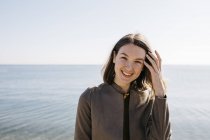 Портрет улыбающейся женщины с морем на заднем плане — стоковое фото