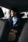Uomo sorridente seduto sul sedile posteriore di una macchina che guarda fuori dal finestrino — Foto stock