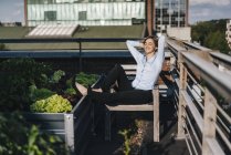 Businesswoman relaxing in his urban rooftop garden — Stock Photo