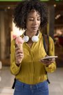 Retrato de mujer con cono de helado mirando el teléfono celular - foto de stock