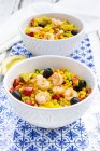 Paella with rice, bell pepper, tomato, artichoke, pea, black olive, curcuma and shrimps — Stock Photo