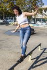 Mujer joven con auriculares balanceándose sobre raíl en la ciudad - foto de stock