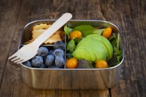 Pranzo scatola di insalata di foglie, avocado, mirtilli, pomodori e cracker — Foto stock