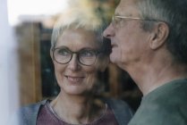 Fiduciosa coppia anziana guardando fuori dalla finestra — Foto stock