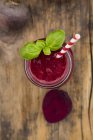 Glass of beet root smoothie garnished with basil leaves — Stock Photo