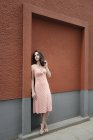 Bella donna in piedi in strada, appoggiata al muro — Foto stock