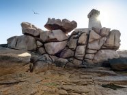 Francia, Bretagne, Plougrescant, Costa di Granito Rosa, formazione rocciosa a Phare de Mean Ruz contro il sole — Foto stock