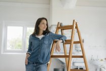 Pretty woman leaning on ladder — Stock Photo