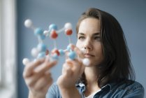 Científica que estudia el modelo de molécula, buscando soluciones - foto de stock