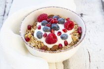 Ciotola di muesli con yogurt greco, quinoa schioccata, lamponi, mirtilli e semi di melograno — Foto stock