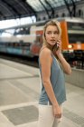 Молодая женщина по мобильному телефону на вокзале оглядывается вокруг — стоковое фото