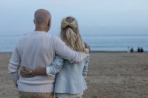 Spanien, Barcelona, Rückansicht eines älteren Paares, das sich in der Abenddämmerung am Strand umarmt — Stockfoto