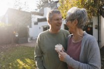 Happy senior couple with cup of coffee in garden — Stock Photo