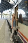 Young woman with cell phone entering a train at the train station — Stock Photo