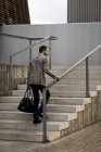 Businessman with bag walking upstairs in the city — Stock Photo