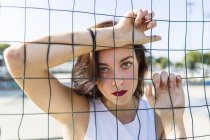 Portrait of young woman behind fence — Stock Photo