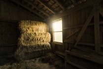 Traditionelle Bauernscheune mit Strohballen und Licht, das durch Fenster kommt — Stockfoto