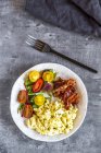 Scrambled eggs with fried bacon and salad with tomato, low carb, from above — Stock Photo