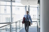 Happy businessman carrying surfboard in office — Stock Photo